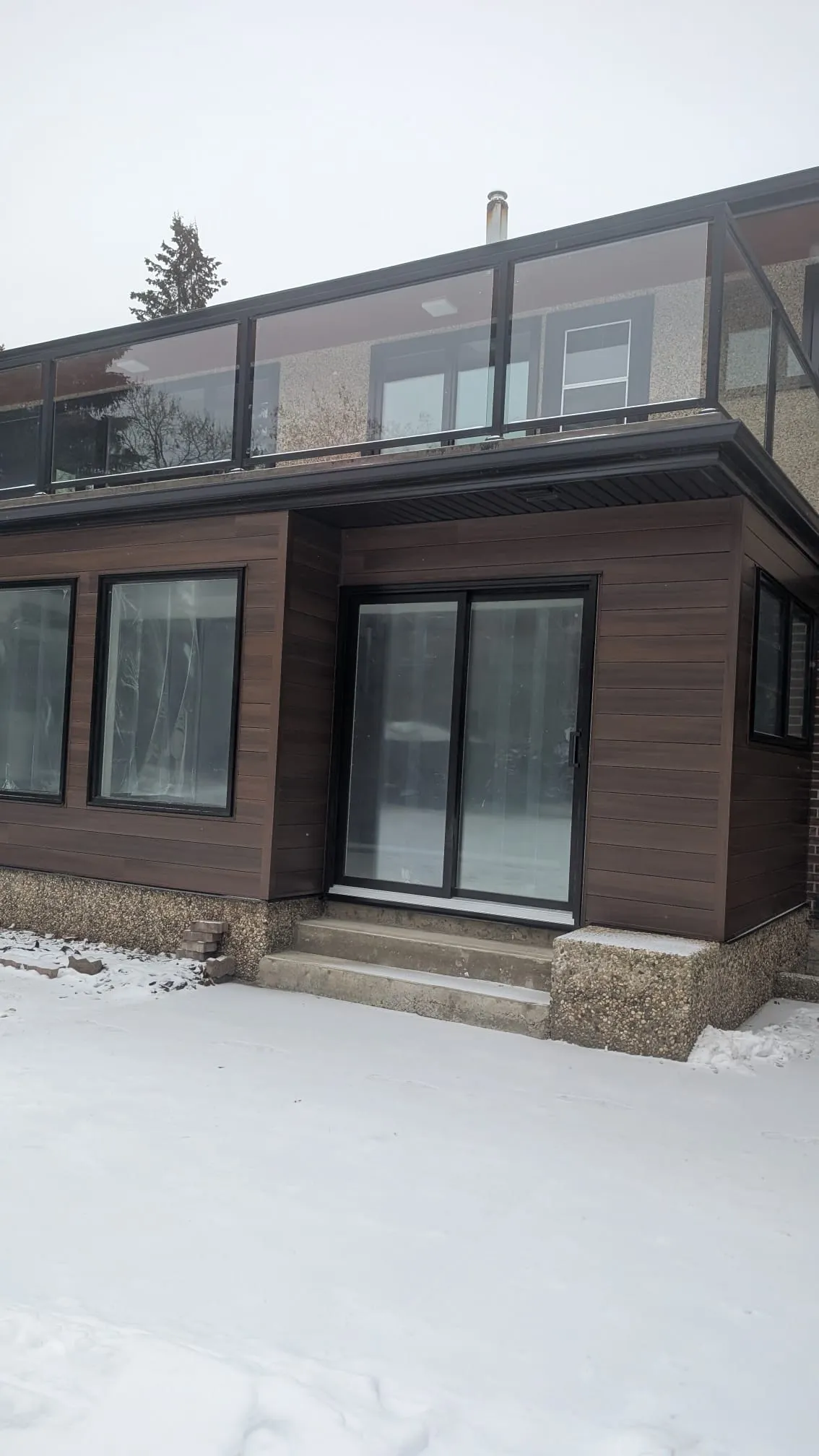ACR Construction modern dark brown siding with glass railing balcony